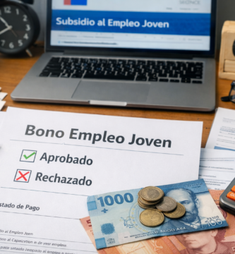 Escritorio con computador, calculadora, documentos y billetes chilenos que representa los resultados, pagos y rechazo del Bono Empleo Joven.